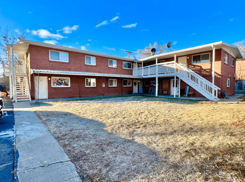 A red brick house with a white porch and a white fence.